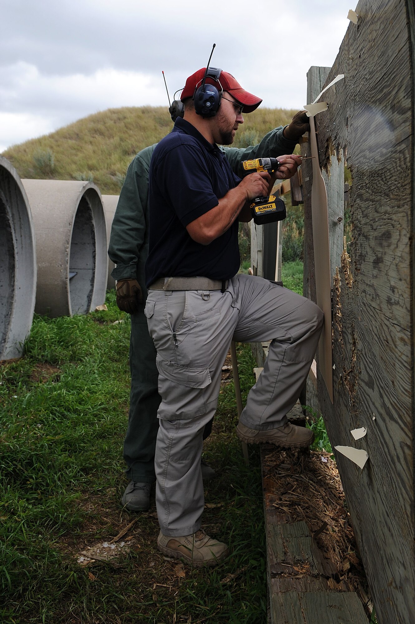 Jeremy Smith, 5th Security Forces Squadron Combat Arms instructor, screws in a background to place the target over for M240B machine gun training at Minot Air Force Base, N.D., Aug. 4, 2016. Smith made the transition from Active Duty Air Force to the Reserve and now works as a civilian in CATM at Minot AFB. (U.S. Air Force photo/ Senior Airman Kristoffer Kaubisch)