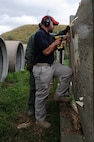 Jeremy Smith, 5th Security Forces Squadron Combat Arms instructor, screws in a background to place the target over for M240B machine gun training at Minot Air Force Base, N.D., Aug. 4, 2016. Smith made the transition from Active Duty Air Force to the Reserve and now works as a civilian in CATM at Minot AFB. (U.S. Air Force photo/ Senior Airman Kristoffer Kaubisch)