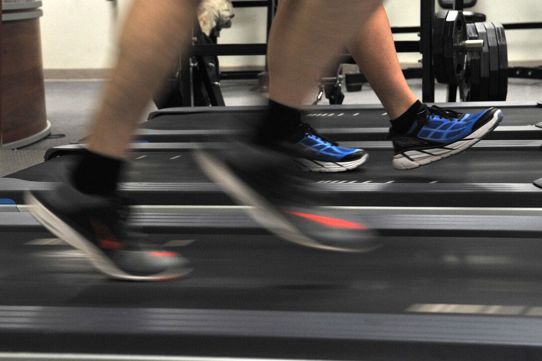 A participant runs as another warms up during a running clinic at the Carswell Field House on Goodfellow Air Force Base, Texas, July 27, 2016. The participant’s running technique was filmed to show him what he was doing right or what could be improved. (U.S. Air Force photo by Staff Sgt. Laura R. McFarlane/Released)