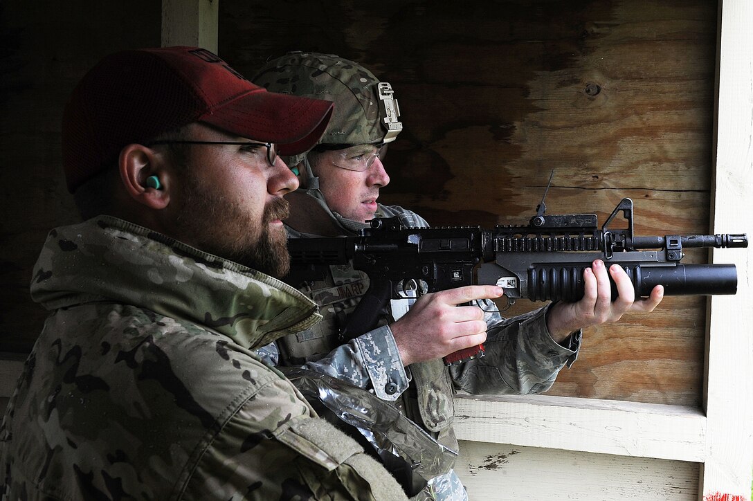 Jeremy Smith, Combat Arms instructor, looks on as a Security Forces member fires an M-203 grenade launcher  during annual firing for defenders at Minot Air Force Base, N.D., June 15, 2016. Prior to firing, the defenders learned how to break down the M-203 and clean it. To carry the weapon, defenders must qualify annually. (U.S. Air Force photo/Senior Airman Kristoffer Kaubisch)