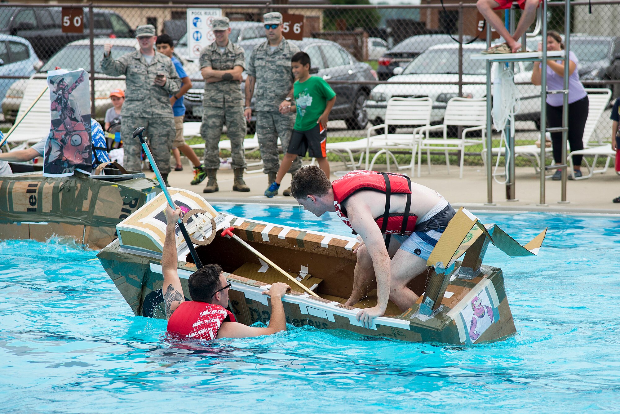 Members of the 375th Comptroller Squadron team attempt to get back into their boat during the annual boat regatta at Scott Air Force Base, Ill., Aug. 5, 2016. They were unable to stabilize their boat and ended up sinking prior to completing the race. (U.S. Air Force photo by Tech. Sgt. Jonathan Fowler)