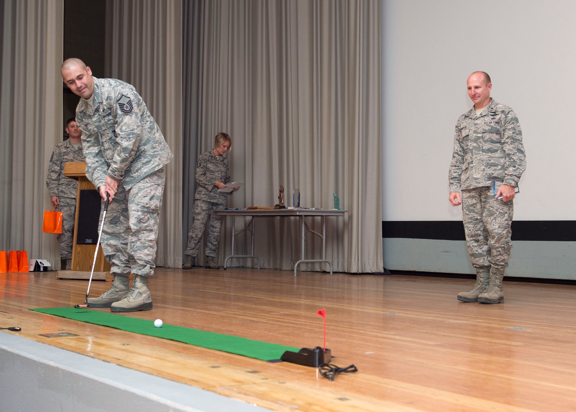 Master Sgt. Joseph Duffy, 412th Mission Support Group, attempts a putt on a portable green as Brig. Gen. Carl Schaefer, 412th Test Wing commander, watches during the wing's second quarter awards ceremony Aug. 3 at the base theater. Duffy won Senior Non-commissioned officer of the Quarter. All winners present were given the opportunity to sink a putt in the golf-themed ceremony. (U.S. Air Force photo by Ethan Wagner)