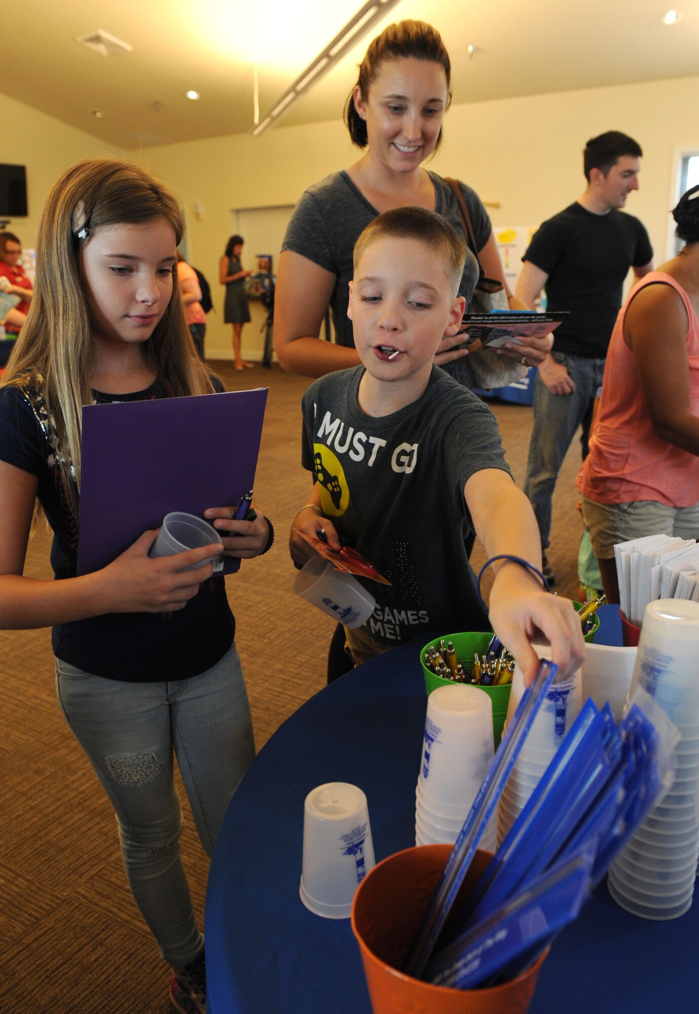 Janell Selvera and her kids, Kalie and Kyle Baker, gather assorted school supplies at the Bay Ridge Community Center during a back-to-school event sponsored by Operation Homefront July 2, 2016, on Keesler Air Force Base, Miss. The event provided military families with backpacks and school supplies. (U.S. Air Force photo by Kemberly Groue/Released)