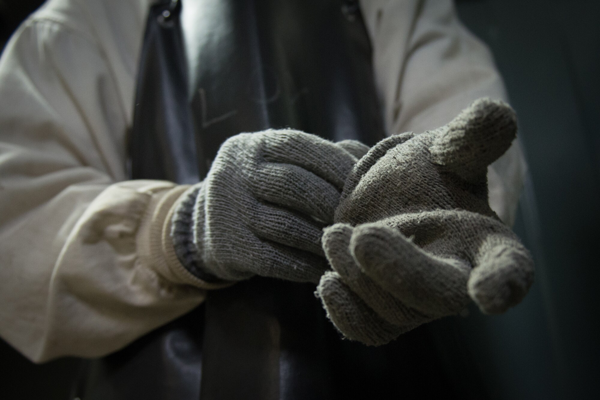 Senior Airman Levi Roark, 673d Logistics Readiness Squadron, fuels distribution journeyman dons wool inserts required for cryogenic servicing, July 22.  He wears the inserts inside the leather overgloves that protect his hands while handling liquid oxygen.