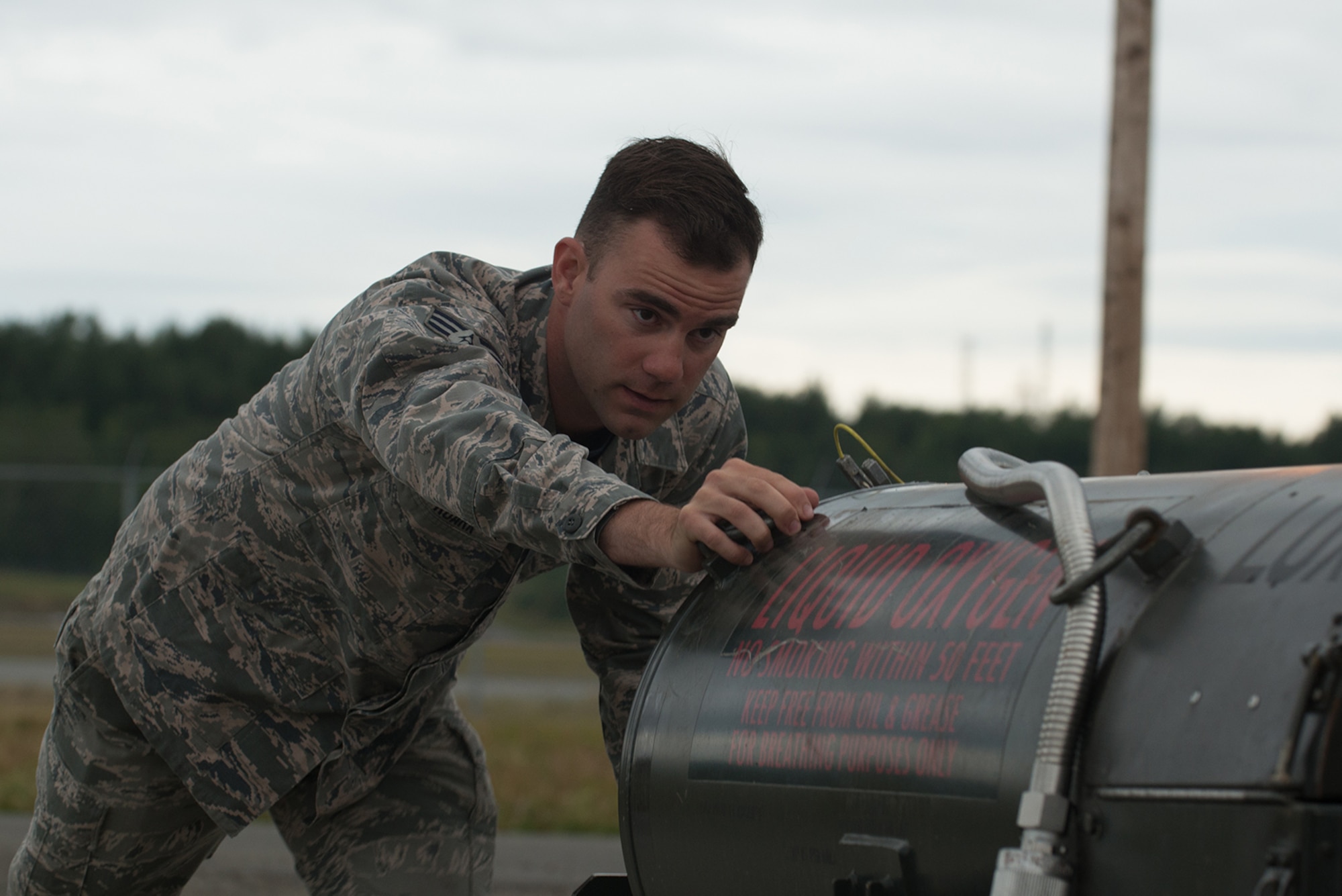 Senior Airman Levi Roark, 673d Logistics Readiness Squadron, fuels distribution journeyman pushes an empty liquid oxygen tank toward the filling station outside the Joint Base Elmendorf-Richardson flightline July 22. The tanks are filled with liquid oxygen which is then loaded into the jets and used as oxygen for the pilots.