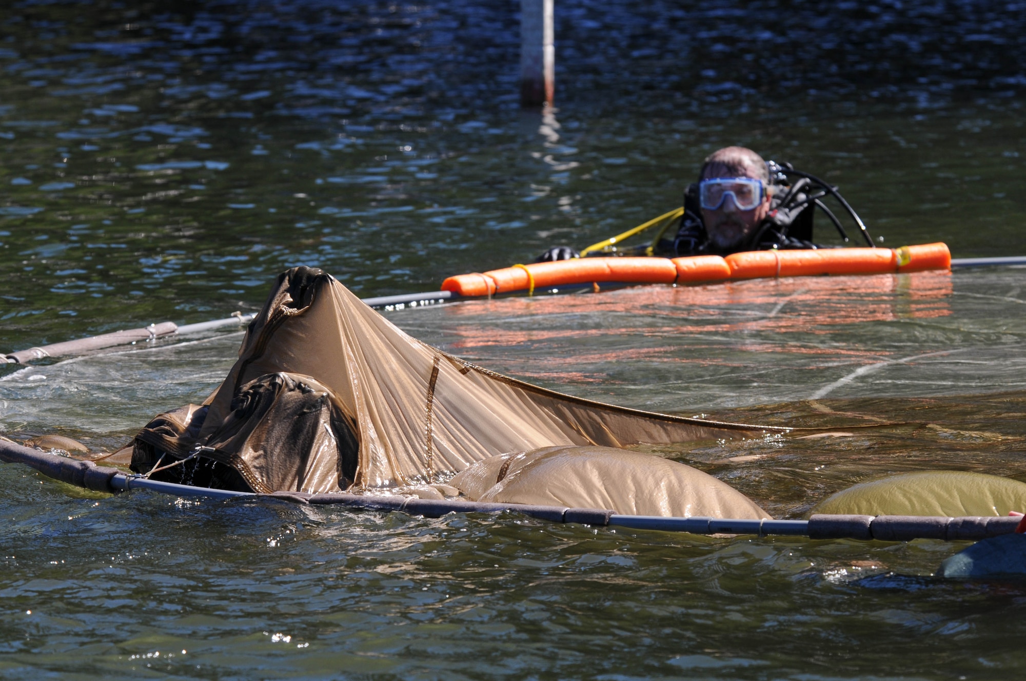 Oregon Air National Guard Maj. Kevin Welch, 114th Fighter Squadron pilot, pulls himself through a water-logged parachute as Capt. Mike Parsons, Klamath Sheriff Dive Rescue, supervises during water survival training at Lake of the Woods near Klamath Falls, Ore., July 22, 2016. Aircrew Flight Equipment members joined with Klamath County Sheriff's Department agencies and members of Coast Guard Sector North Bend to provide Kingsley’s F-15 pilots water survival training in the event of an emergency ejection. (U.S. Air National Guard photo by Staff Sgt. Penny Snoozy)