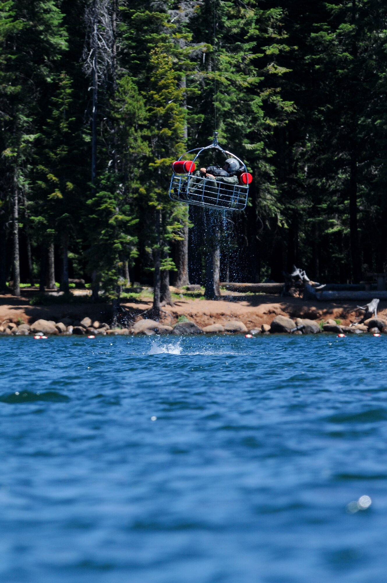 Oregon Air National Guard Capt. Nathan Liptak, 114th Fighter Squadron pilot, sits in a basket loaded by Aviation Survival Technician 3rd Class Brendan Davis, Coast Guard Sector North Bend, during water survival training at Lake of the Woods near Klamath Falls, Ore., July 22, 2016. Aircrew Flight Equipment members joined with Klamath County Sheriff's Department agencies and members of Coast Guard Sector North Bend to provide Kingsley’s F-15 pilots water survival training in the event of an emergency ejection. (U.S. Air National Guard photo by Staff Sgt. Penny Snoozy)