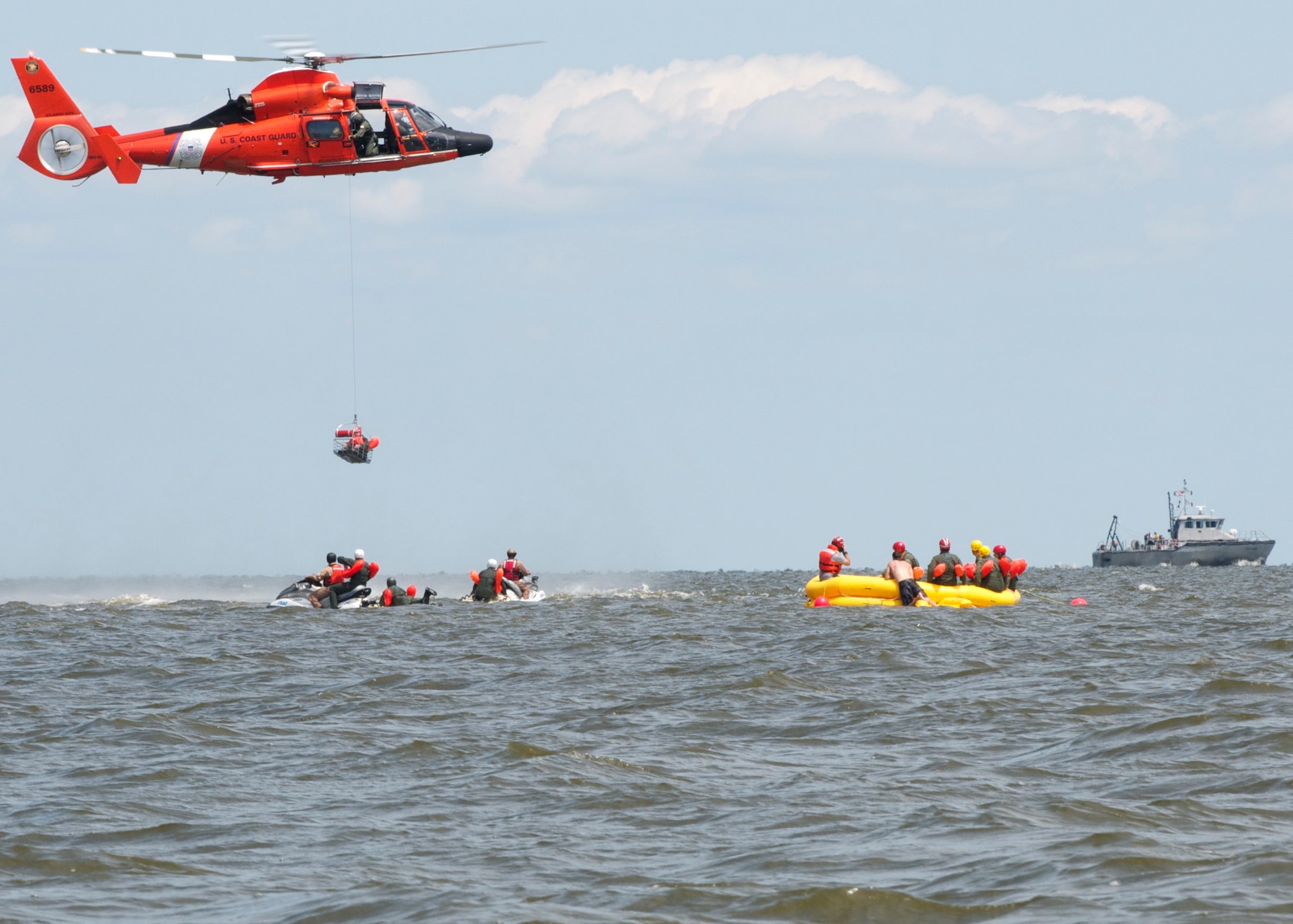 A Dover Air Force Base Airman is basket lifted by a Coast Guard H-65 Dolphin helicopter during water survival training Aug. 6, 2015 at Bowers Beach, Del. Airmen with the 512th Airlift Wing and 436th Airlift Wing performed water survival training focusing on treading water, raft survival, and the basket-lift helicopter evacuation. (U.S. Air Force Photo/ Staff Sgt. Tiffany Lindemann)