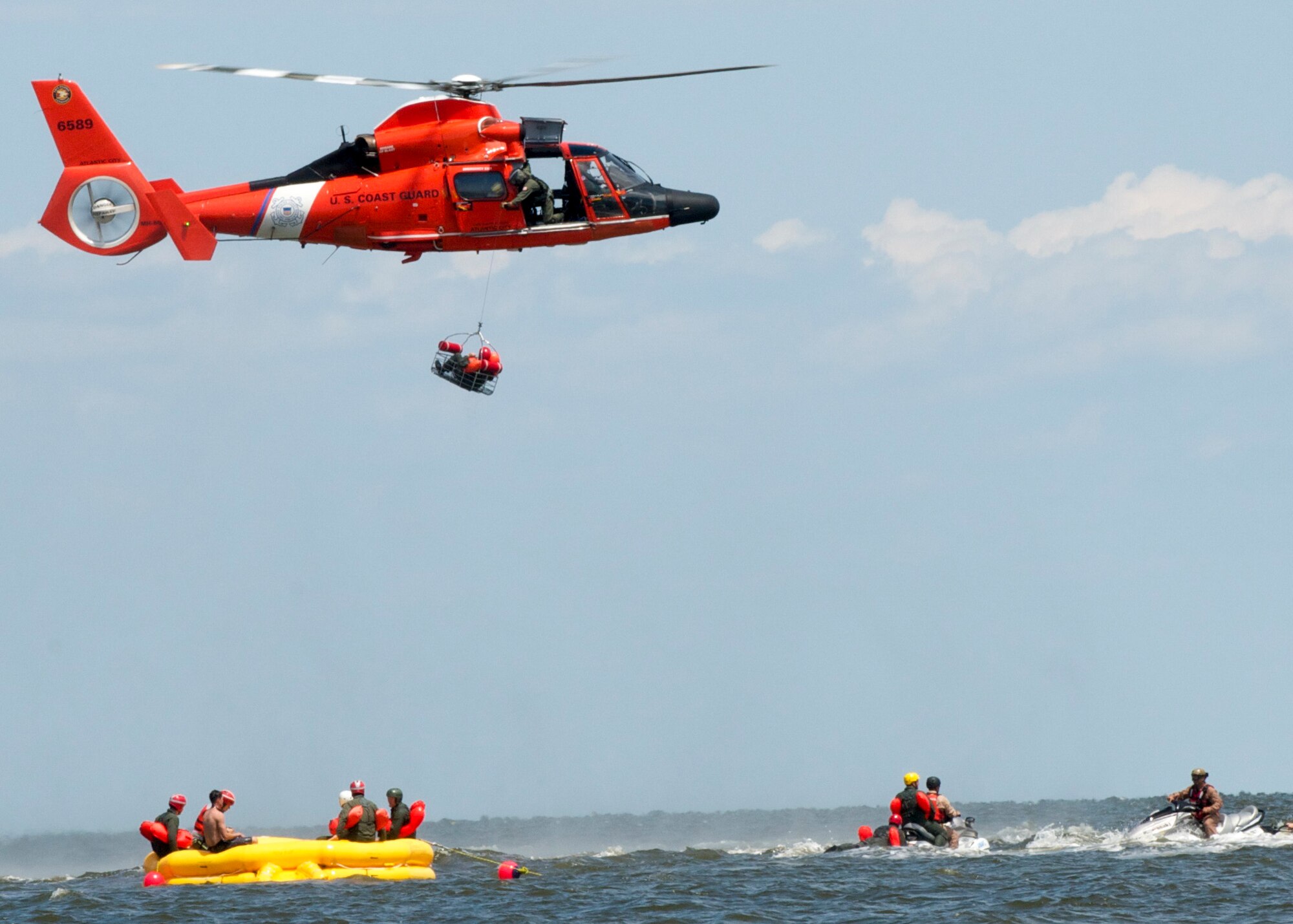 A Dover Air Force Base Airman is basket lifted by a Coast Guard H-65 Dolphin helicopter during water survival training Aug. 6, 2015 at Bowers Beach, Del. Airmen with the 512th Airlift Wing and 436th Airlift Wing performed water survival training focusing on treading water, raft survivial, and the basket-lift helicopter evacuation. (U.S. Air Force Photo/ Staff Sgt. Tiffany Lindemann) 
