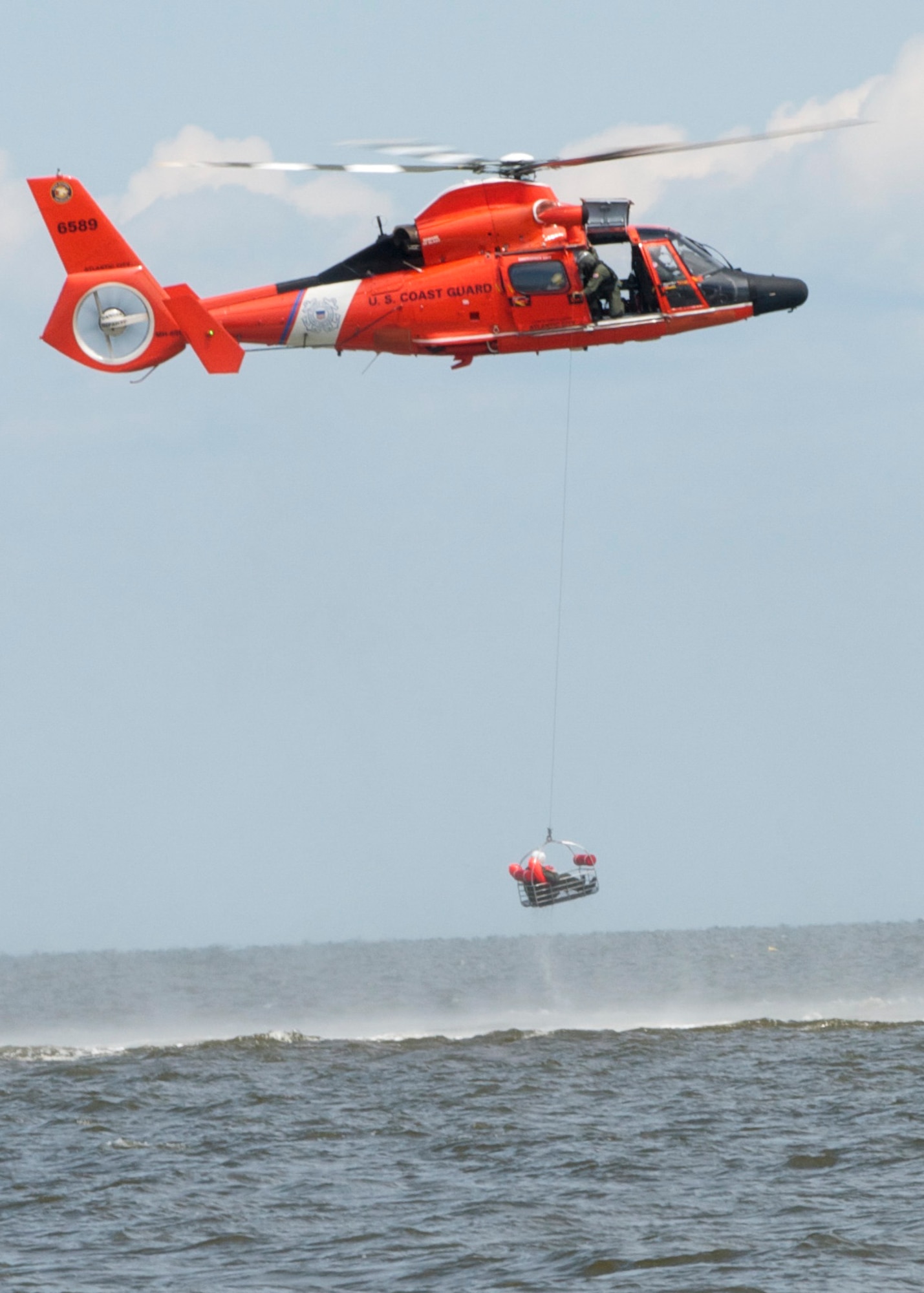 A Dover Air Force Base Airman is basket lifted by a Coast Guard H-65 Dolphin helicopter during water survival training Aug. 6, 2016 at Bowers Beach, Del. Airmen with the 512th and 436th Airlift Wings performed water survival training focusing on treading water, raft survival, and the basket-lift helicopter evacuation. (U.S. Air Force Photo/ Staff Sgt. Tiffany Lindemann)