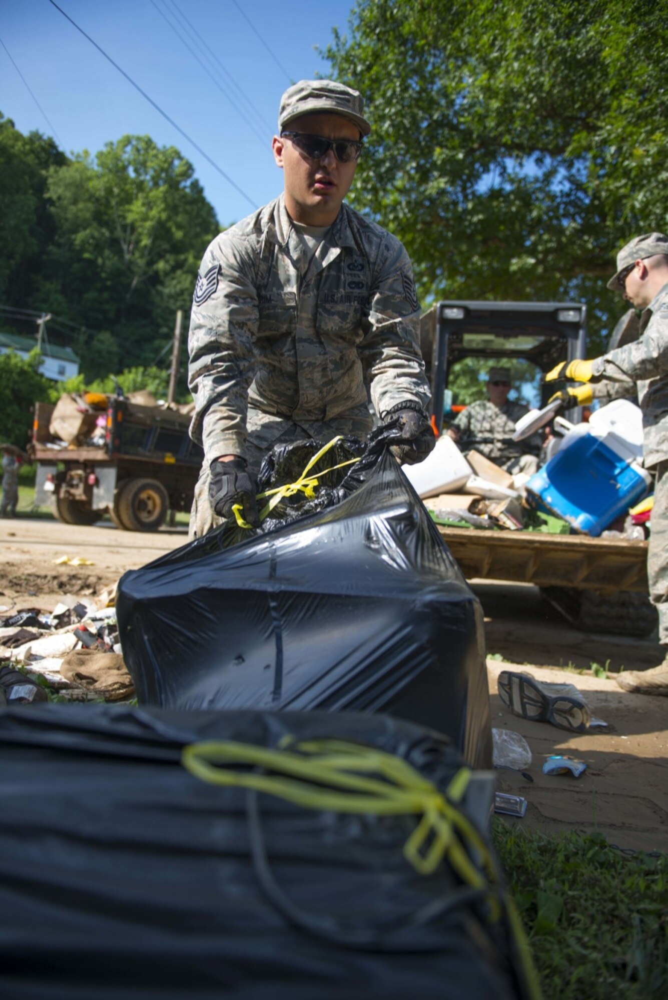 Tech. Sgt. Brian Grim of the 167th Airlift Wing, Martinsburg, W.Va., picks up debris on June 26, 2016 in Clendenin, W.Va. The June 23, 2016 flood was described as a once in 1000 year event leading W.Va. Gov. Earl Ray Tomblin to declare a State of Emergency in 44 of the 55 counties. (United States Air National Guard photo/Tech. Sgt. De-Juan Haley)