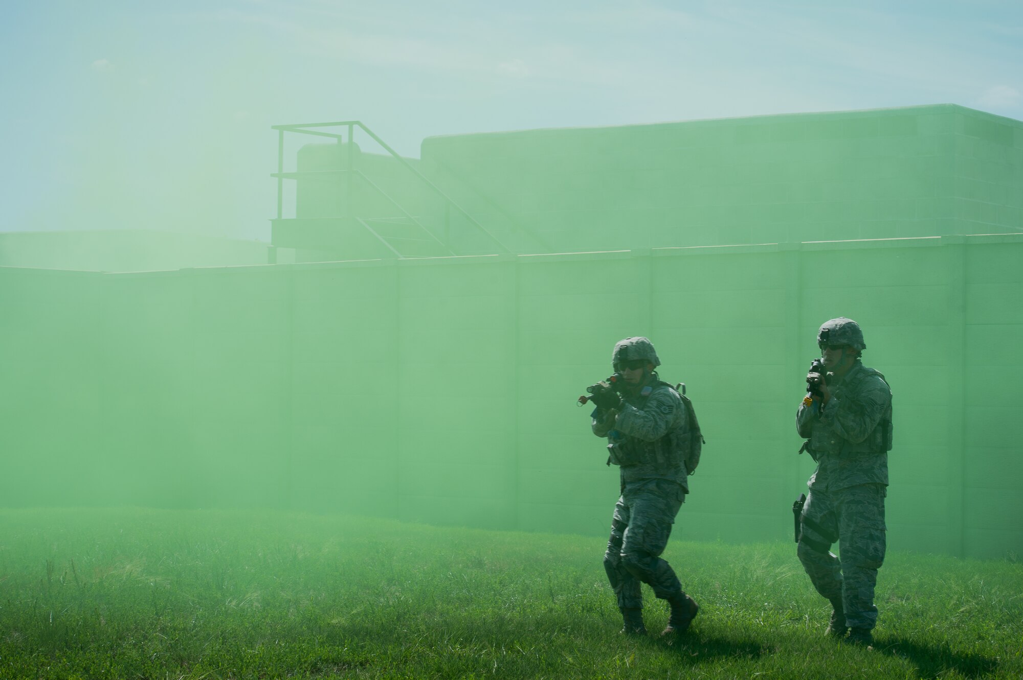 Staff Sgt. Jared Tooley and Senior Airman Eliezer Najera, 137th Security Forces Squadron Airmen, engage a target through green smoke during an urban terrain scenario at Camp Gruber Training Center near Braggs, Okla., Aug. 3, 2016.  Approximately 40 members of the 137 SFS completed annual training from July 29 to Aug, 5, 2016. Airmen participated in extensive training exercises including close combat, weapons, military operations on urban terrain and navigation. (U.S. Air National Guard photo by Senior Airman Tyler Woodward/Released)