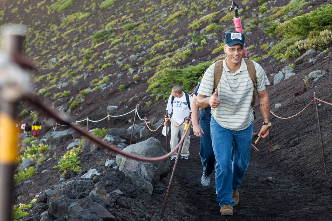 U.S. Marine Corps Sgt. Maj. Jonathan Wyble, Marine Wing Support Squadron (MWSS) 171, sergeant major, based out of Marine Corps Air Station Iwakuni, gives a thumbs-up during the hike up Mount Fuji, Japan, as part of a unit activity July 31, 2016. Marines within the squadron conquered Mount Fuji with a 3,776 meter climb to the peak. Marines bought ‘Kongo-Tsue’ walking sticks and had stamps burned onto them, which signified the location and altitude throughout 10 stations located up the trail. (U.S. Marine Corps photo by Lance Cpl. Aaron Henson)