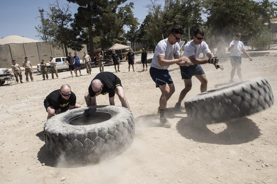 U.S. Army military police and U.S. Air Force security forces members compete in a tire flip, Bagram Airfield, Afghanistan, Aug. 7, 2016. The two branches went head to head in an all or nothing Battle of the Badges competition. Participants endured 100 degree weather to compete in activities that mimic day to day or rescue tasks for security forces members, firemen and military police members. (U.S. Air Force photo by Tech. Sgt. Tyrona Lawson)