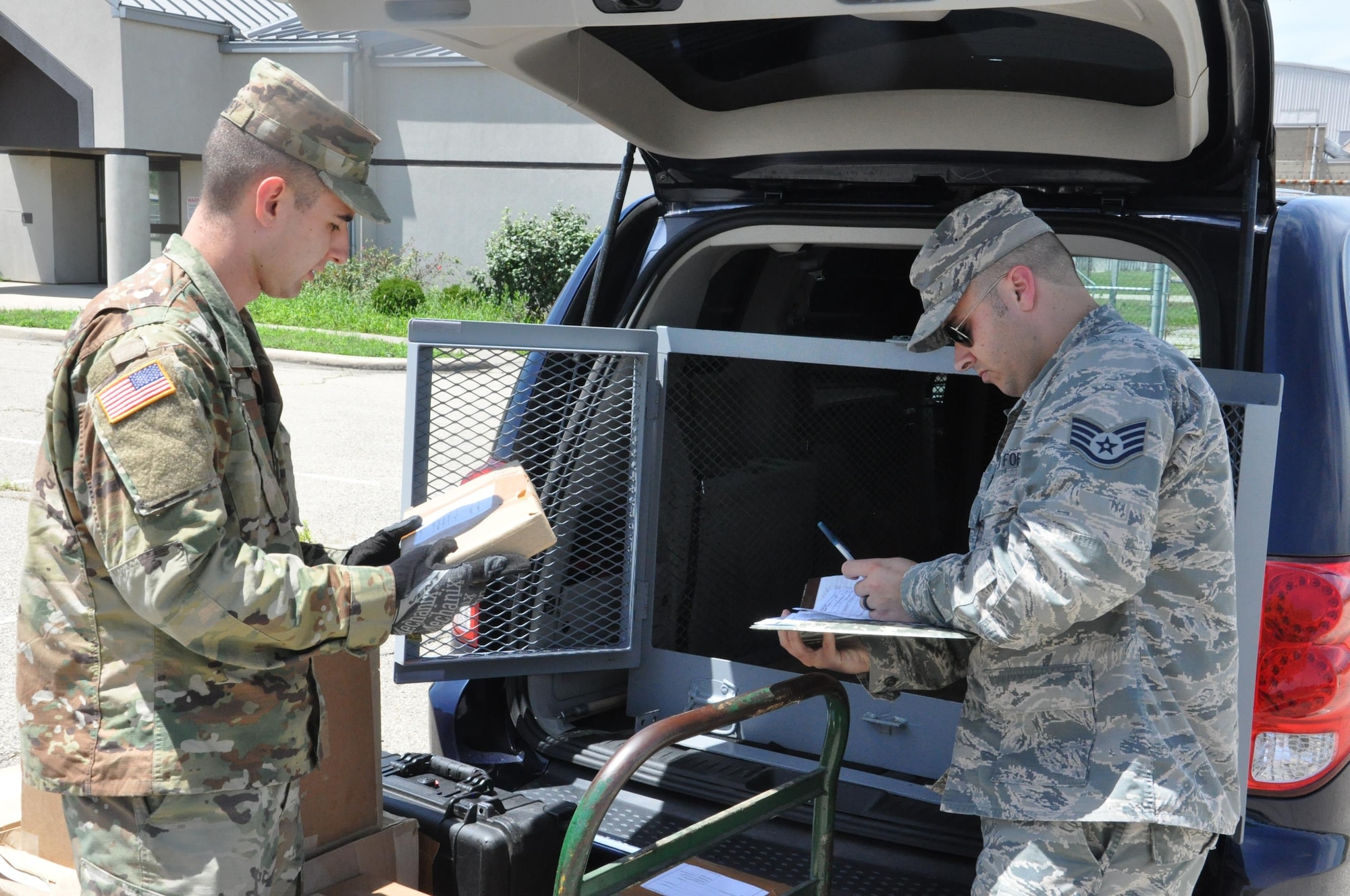 Army Specialist Andrew Caskey and Air Force Staff Sgt. Alan Ferry of the WPAFB Defense Courier Station load material for delivery prior to departing on a mission. (U.S. Air Force photo/Bill Hancock)
