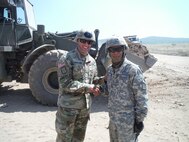 Pvt. Endry Villasmil, a heavy equipment operator with the 766th Engineer Company (Horizontal), 841st Engineer Battalion, U.S. Army Reserve, is presented a command team coin for excellence by Maj. Chrustowski, Headquarters and Headquarters Company, 841st Engineer Battalion. Villasmil was recognized for his skill in operating a front-end loader (pictured in the background) in a safe and efficient manner allowing the unit to maintain full dump trucks and maximize progress on the construction sites. (U.S. Army photo by Capt. Jose F. Lopez Jr., 841st Eng. Bn., United States Army Reserve)