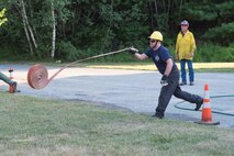 Capt. Joe Segien, New Boston Fire Department firefighter, throws a hose during the NBFD’s “First Helmet” competition at New Boston Air Force Station, New Hampshire, Wednesday, July 27, 2016. Seigen and other firefighters participated in the competition that tested the speed and efficiency of each department member. (Courtesy photo)