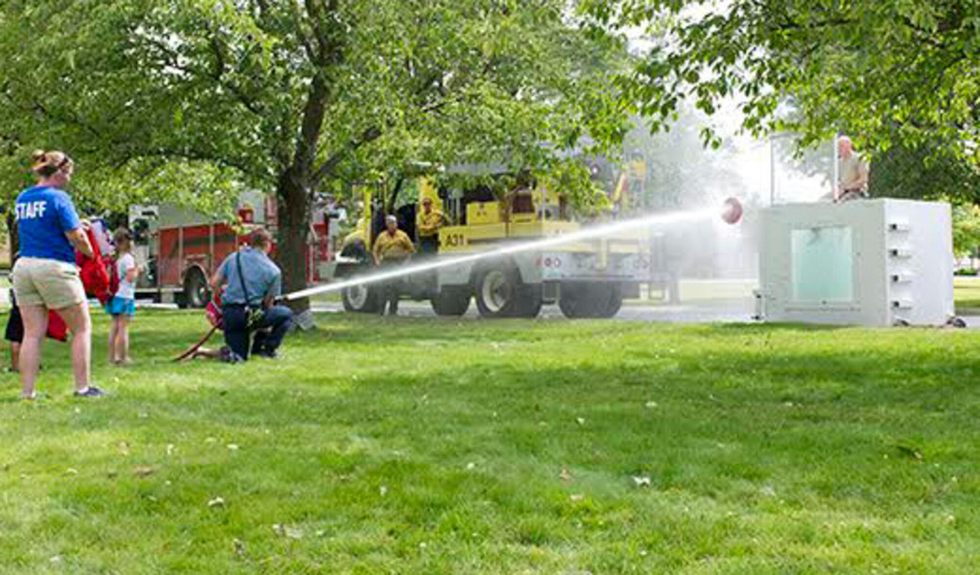 Alex Turner, Airway Heights Fire Department firefighter, helps children spray water from a fire hose at a target on a water dunk tank during the Fire Prevention Youth Camp Aug. 3, 2016, at Fairchild Air Force Base, Wash. To finish off the Fire Prevention Youth Camp children experienced what it
was like to shoot a fire hose at a simulated fire target. (U.S. Air Force photo/Senior Airman Nick Daniello)
