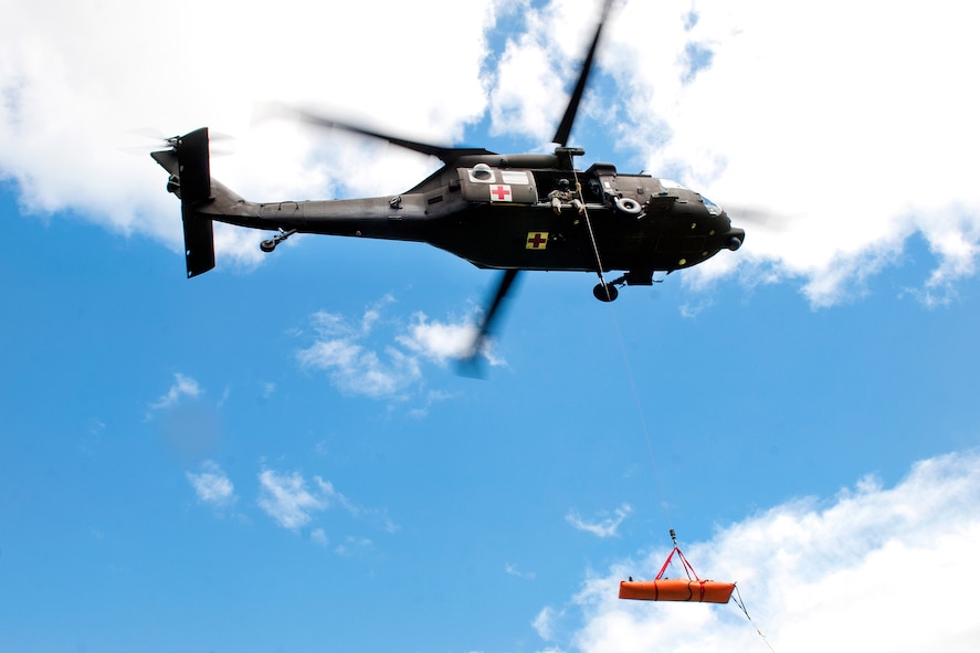 An HH-60M Black Hawk helicopter crew hoists a simulated casualty.