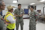 Maj. Enrique Romero, a physician in the Chilean Air Force, right, discusses medical operations with Col. Jonathan MacClements, a physican in the Texas State Guard, center, and Eduardo Olivarez, the chief administrative officer for the Hidalgo County Department of Health and Human Services (DHHS) at an Operation Lone Star site in Pharr, Texas, July 27, 2016. 