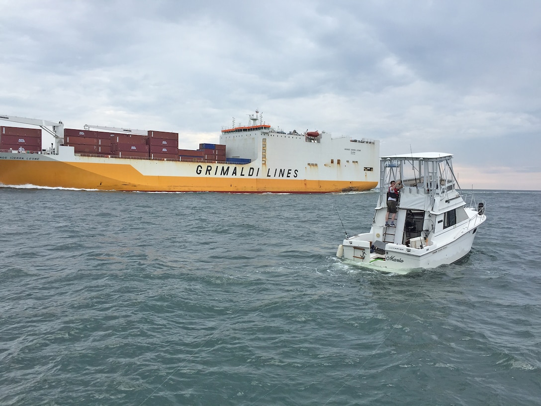 A small vessel in distress is seen near Cape Henry Channel as a large cargo vessel passes by Sunday, Aug. 7, 2016. U.S. Army Corps of Engineers, Baltimore District Survey Vessel LINTHICUM assisted the vessel in distress by communicating with the cargo vessel to ensure they were aware of the nearby smaller vessel and by sharing the location of the disabled small vessel with the Coast Guard, who quickly arrived and provided further assistance.
