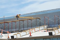 A construction worker moves boards on the roof of a building, August 3, 2016, at McConnell Air Force Base, Kan. The building will be the home of the Regional Maintenance Training Facility, which is where KC-46 Pegasus crew chiefs will be trained. (U.S. Air Force photo/Airman Erin McClellan)