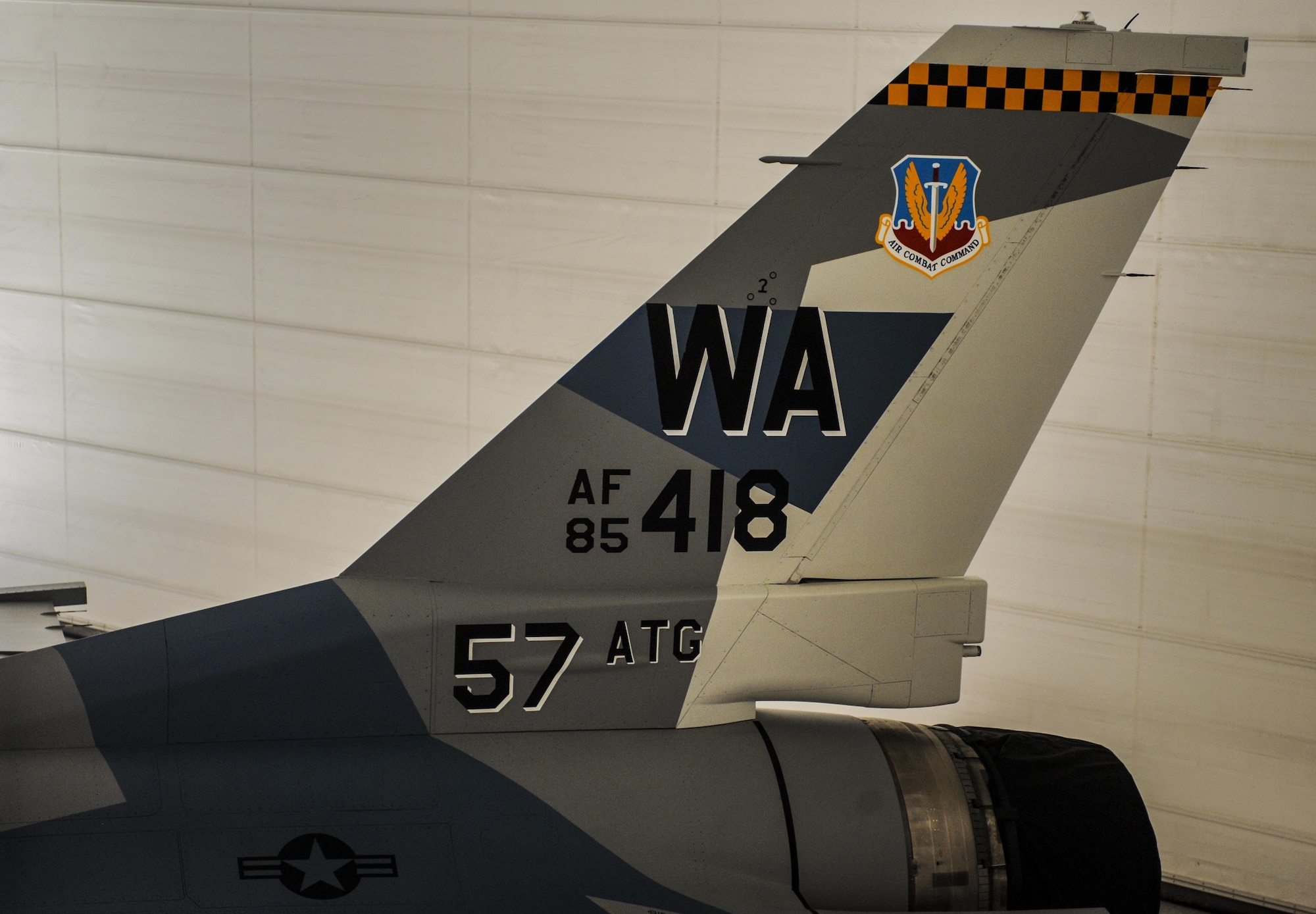 The tail of an F-16 Fighting Falcon, assigned to the 64th Aggressor Squadron, with the new “splinter” paint scheme sits in the U.S. Air Force Thunderbird hangar at Nellis Air Force Base, Nev., during the 57th Adversary Tactics Group change of command ceremony Aug. 5, 2016. To represent threats more accurately, the 64th AGRS looks for any and all ways to try to emulate the threats that are opposing combat air forces. (U.S. Air Force photo by Airman 1st Class Kevin Tanenbaum/Released)