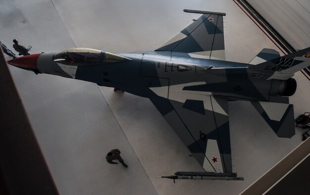 Airmen, attending the 57th Adversary Tactics Group change of command ceremony, take the first look at the new F-16 Fighting Falcon, assigned to the 64th Aggressor Squadron, paint scheme in the U.S. Air Force Thunderbird hangar at Nellis Air Force Base, Nev., Aug. 5, 2016. This one of the kind “splinter” scheme is one of two different paint schemes that will be introduced in the coming months. (U.S. Air Force photo by Airman 1st Class Kevin Tanenbaum/Released)