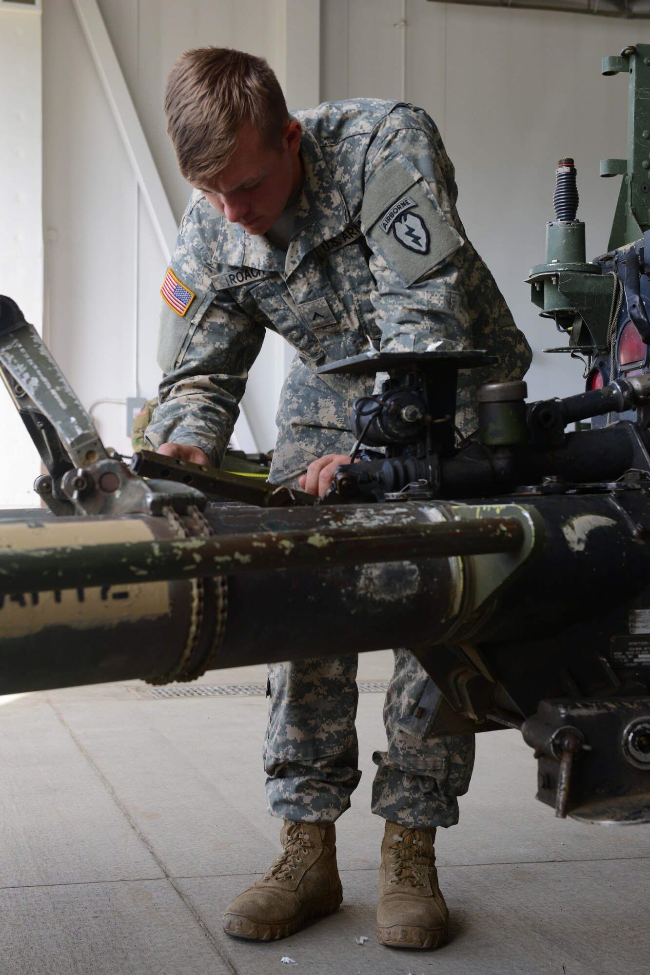 Pvt.Koleman Roach A Battery, 2nd Battalion, 377th Parachute Field Artillery Regiment advance party, scrapes a label off an M119 Howitzer at Joint Base Elmendorf-Richardson, Alaska, August 3, 2016. A round from the howitzer can travel just over eight miles. (U.S. Air Force photo by Airman 1st Class Javier Alvarez)