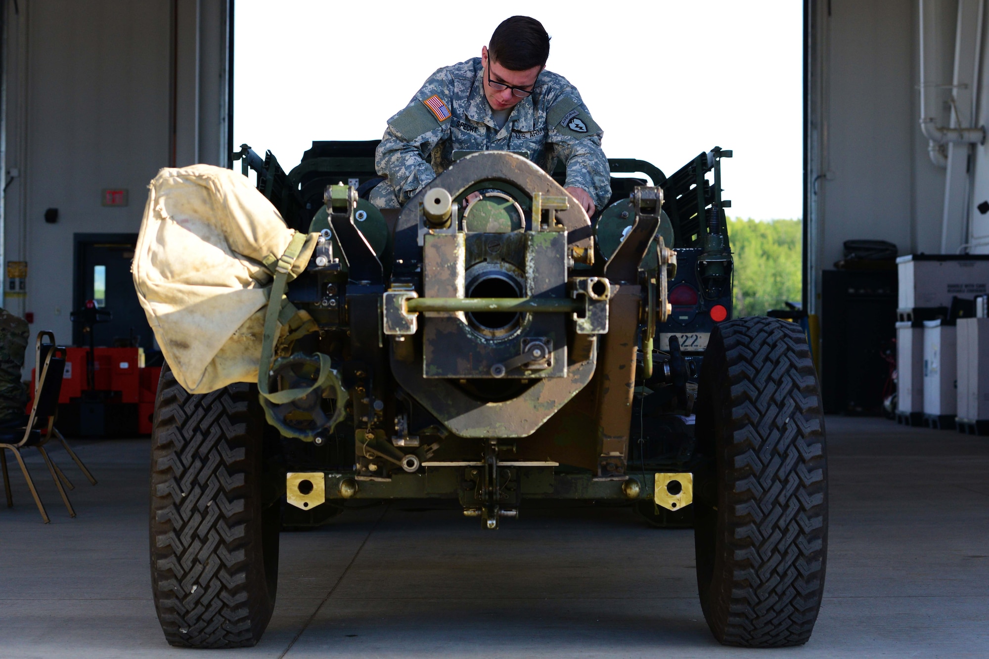 Army Spc. Cody Specht, A Battery, 2nd Battalion, 377th Parachute Field Artillery Regiment cannon crewmember, scrapes a label off an M119 Howitzer at Joint Base Elmendorf-Richardson, Alaska, August 3, 2016. The M119 is a lightweight towed howitzer in service with the US Army. The howitzer provides direct and indirect fire support to the forces deployed in combined arms operations. (U.S. Air Force photo by Airman 1st Class Javier Alvarez)