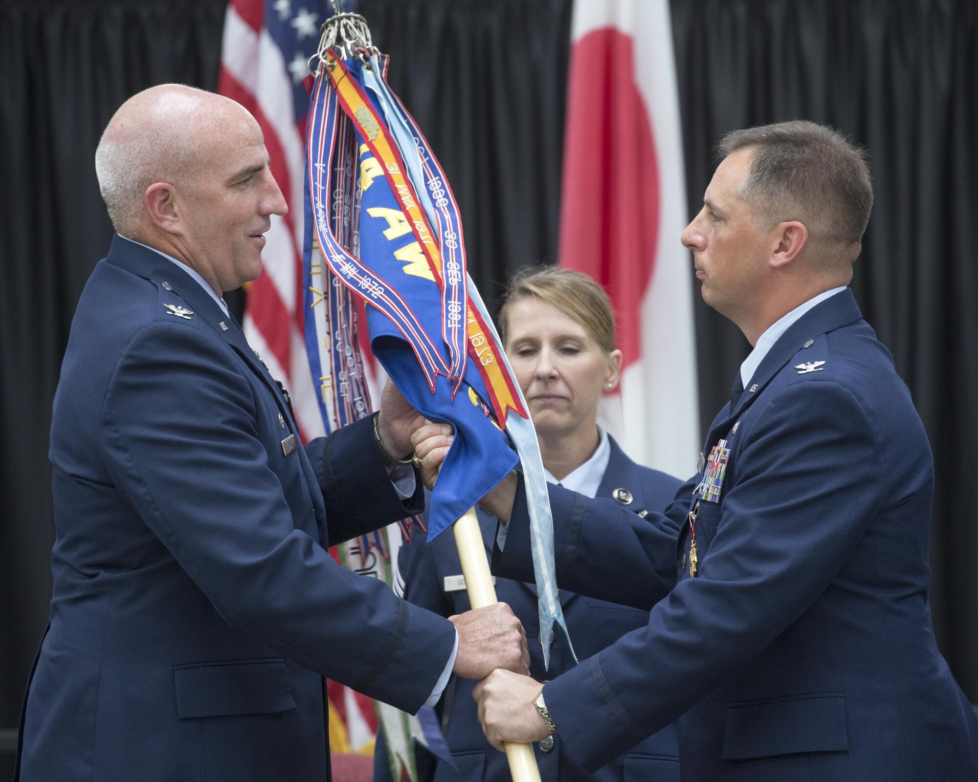 Col. Kenneth Moss, left, 374th Airlift Wing commander, receives the guidon from Col. Scott Maskery, right, outgoing 374th Mission Support Group commander, during a change of command ceremony at Yokota Air Base, Japan, Aug. 8, 2016. The guidon is a tradition dating back to the Roman Empire; military units would carry a banner with their emblem into battle. The passing of the guidon to the new commander signifies the start of  responsibility. (U.S. Air Force photo by Yasuo Osakabe/Released) 