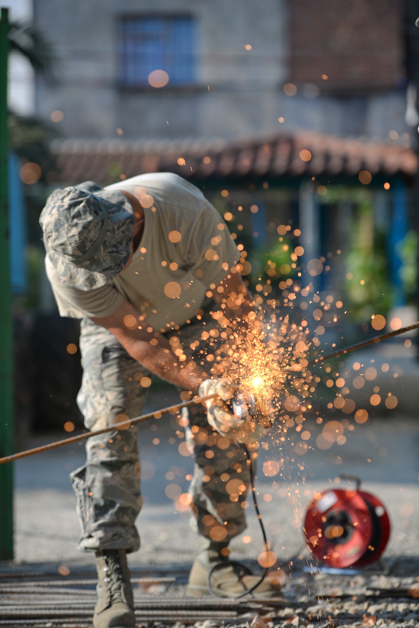 A picture of U.S. Air Force Senior Master Sgt. Todd Butcher, New Jersey Air National Guard civil engineer, using an angle grinder with an abrasive disc to cut a reinforcing bar.