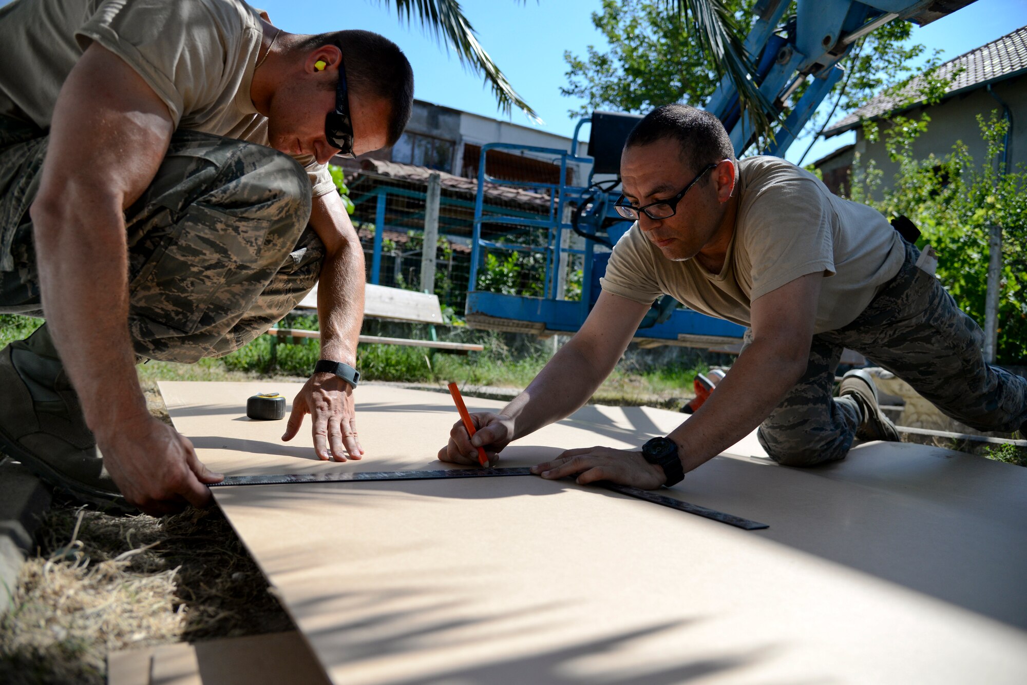 A picture of U.S. Air Force Senior Airman Kristopher Christensen, and Airman 1st Class Oscar Marrou-Tonkovic, civil engineers with the New Jersey Air National Guard, measuring and marking wall board for cutting.