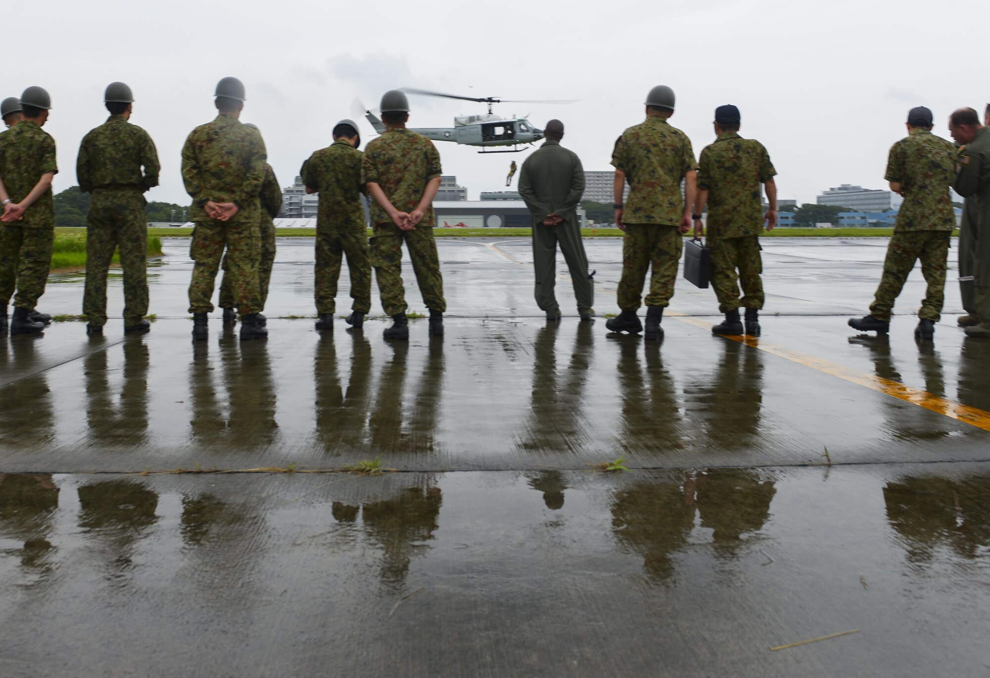 Members of the Japan Ground Self Defense Force watch the 459thth Airlift Squadron familiarize with a rescue operation at Camp Tachikawa, July 26, 2016. Eastern Army Helicopter invited the 459th Airlift Squadron to attend the 2nd Tachikawa Helicopter Conference as friends and valuable allies. U.S. forces have supported Japan disaster-relief efforts in the past and staying in communication helps ensure we are prepared to do so again.  (U.S. Air Force photo by Airman 1st Class Elizabeth Baker/Released)
