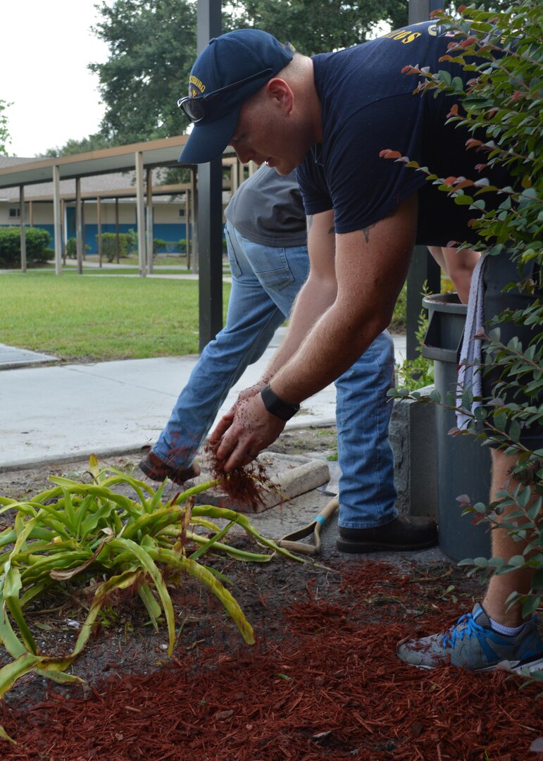 Cryptologic Technician Technical Chief Devin Simpson spreads mulch on the grounds of Oak Hill Academy in Jacksonville, Fla. Simpson, a Sailor with Southeast Regional Maintenance Center (SERMC) in Mayport, Fla., led 20 Sailors who volunteered to help put the finishing touches inside the classrooms and general clean-up around the campus prior to the new student body orientation Aug. 12. Photo by Scott Curtis
