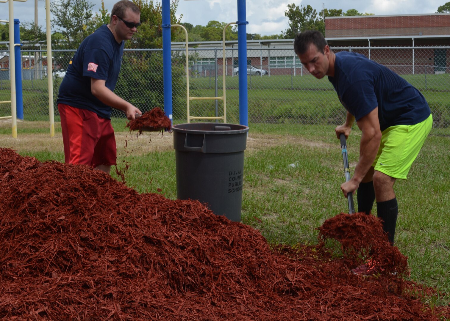 Machinist's Mate 1st Class Brian Hill (R) and Engineman 1st Class Robin Mosely (L) shovel mulch into a makeshift wheel-barrow at Oak Hill Academy in Jacksonville, Fla. Hill and Mosely are Sailors with Southeast Regional Maintenance Center (SERMC) in Mayport, Fla. Both volunteered to help clean, assemble furniture and prepare classrooms for the 2016-2017 school year. SERMC provides surface ship maintenance, modernization and technical expertise in support of the ships of the US Navy. Photo by Scott Curtis
