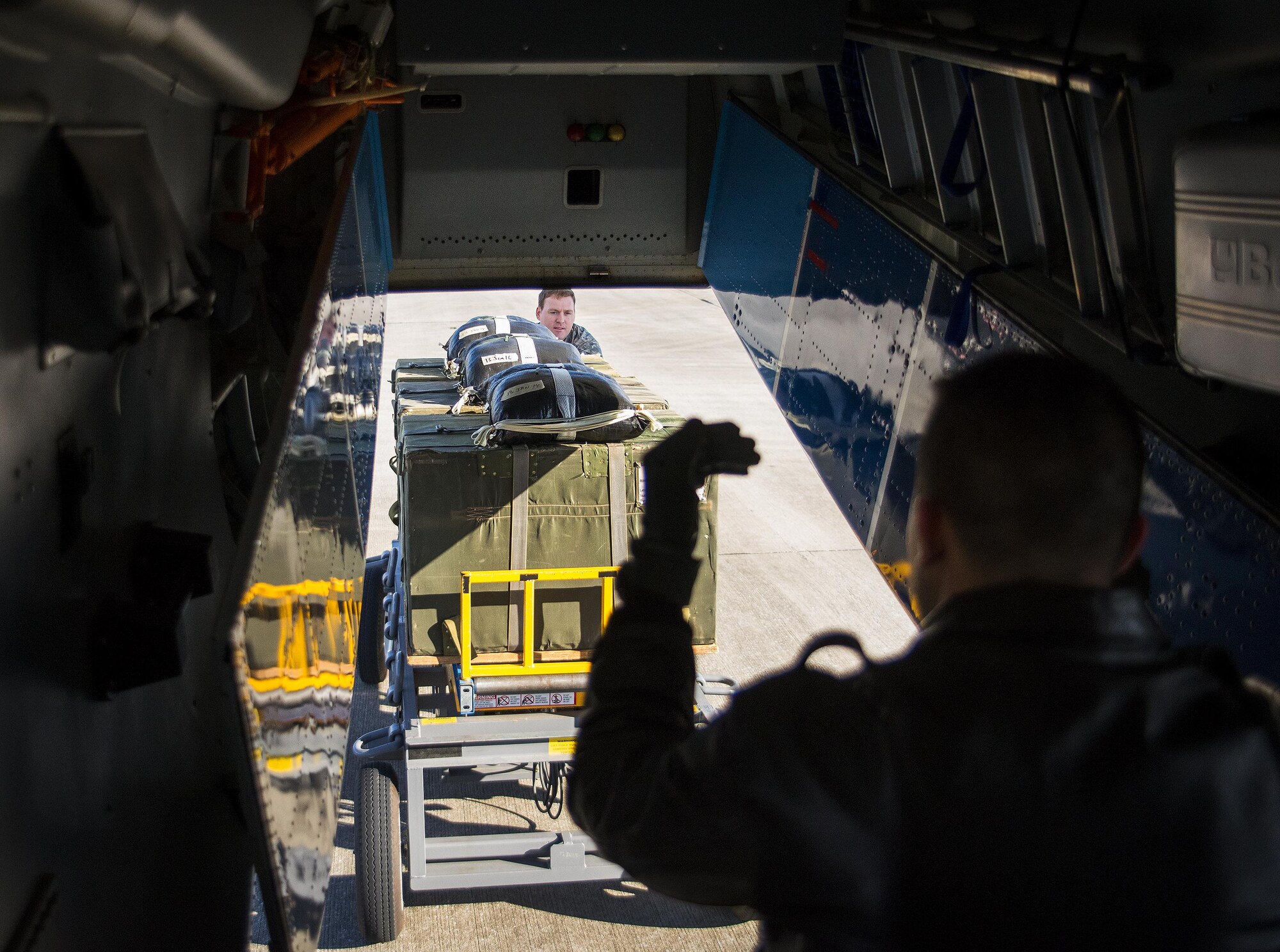 A loadmaster helps guide Staff Sgt. Justin Spencer, 919th Special Operations Logistics Readiness Squadron, toward a C-145 Skytruck to load parachute bundles for a training sortie at Duke Field, Fla.  The 300-pound bundles are loaded so new loadmasters can perform their initial airdrop training and prior-qualified Airmen can maintain proficiency.  (U.S. Air Force photo/Sam King)  