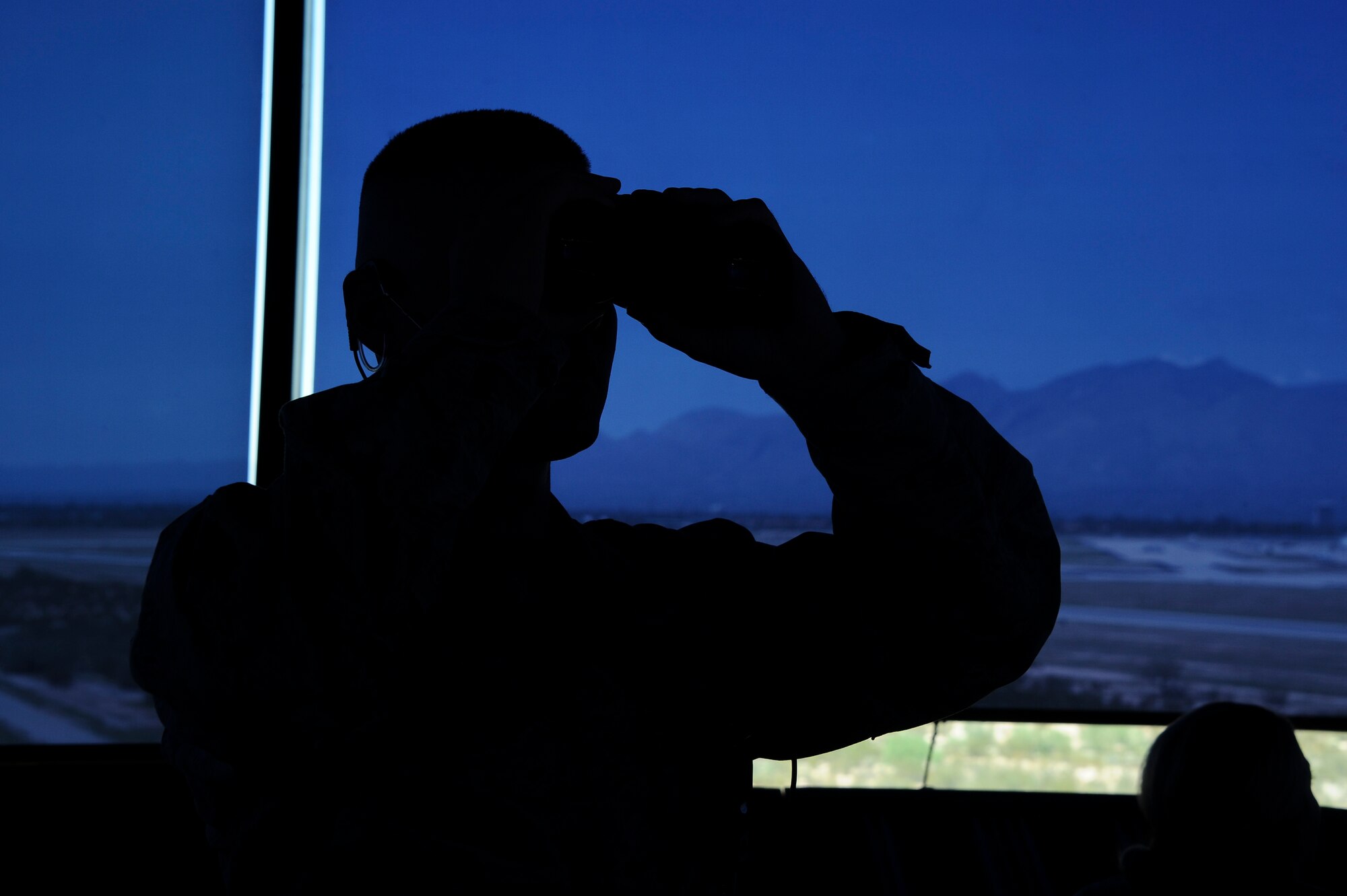 U.S. Air Force Senior Airman Kimo Lagapa-Talbott, 355th Operations Support Squadron air traffic controller, uses a pair of binoculars to monitor incoming aircraft at Davis-Monthan Air Force Base, Ariz., July 29, 2016. ATCs observe and relay flight instructions for aircraft takeoffs and landings. (U.S. Air Force photo by Airman 1st Class Mya M. Crosby)