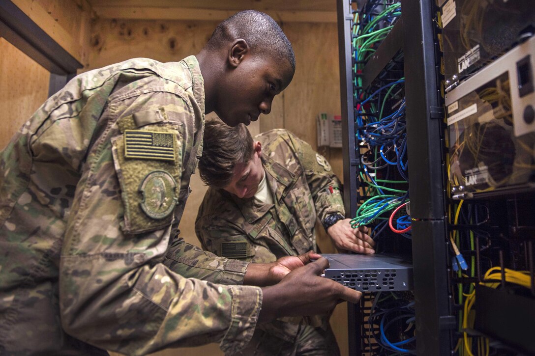 Air Force Senior Airman Isiah Chaney, right, and Airman 1st Class Reginald Maffett install a switch panel at Bagram Airfield, Afghanistan, July 29, 2016. Chaney and Maffett are network management technicians assigned to the 455th Expeditionary Communications Squadron. Switches provide network connectivity to devices such as phones and computers. Air Force photo by Senior Airman Justyn M. Freeman 