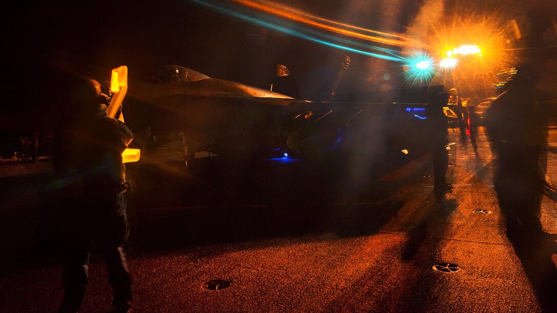 A sailor directs a Navy F/A-18E Super Hornet assigned to Strike Fighter Squadron 137 during night operations on the flight deck of the aircraft carrier USS Carl Vinson in the Pacific Ocean, Aug. 5, 2016. Navy photo by Petty Officer 2nd Class D’Andre L. Roden