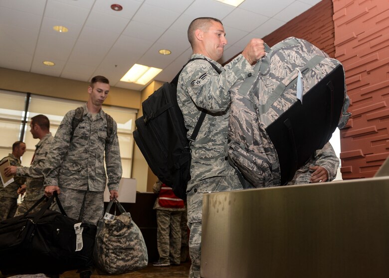 Senior Airman Jeremy Holloway, a crew chief assigned to the 28th Aircraft Maintenance Squadron, lifts his duffle bag onto a conveyor belt at Ellsworth Air Force Base (AFB), S.D., Aug. 1, 2016. This is the largest deployment Ellsworth AFB has conducted in the last 10 years, with approximately 300 Airmen being deployed to Andersen AFB, Guam. (U.S. Air Force photo by Airman 1st Class Sadie Colbert)