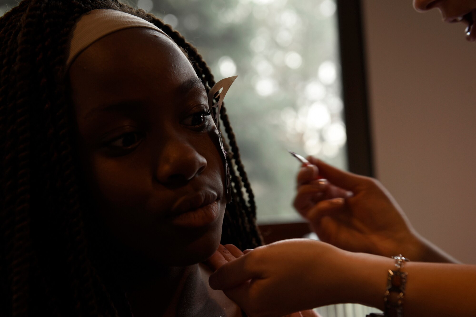Sanaa Ford gets her face painted by a volunteer at the Family Festival and Concert at The Club on Peterson Air Force Base, Colo., Aug. 6, 2016. The event had face painting, a bouncy obstacle course, carpet bowling, games and dancing to music from rock band 6035. (U.S. Air Force photo by Senior Airman Rose Gudex)