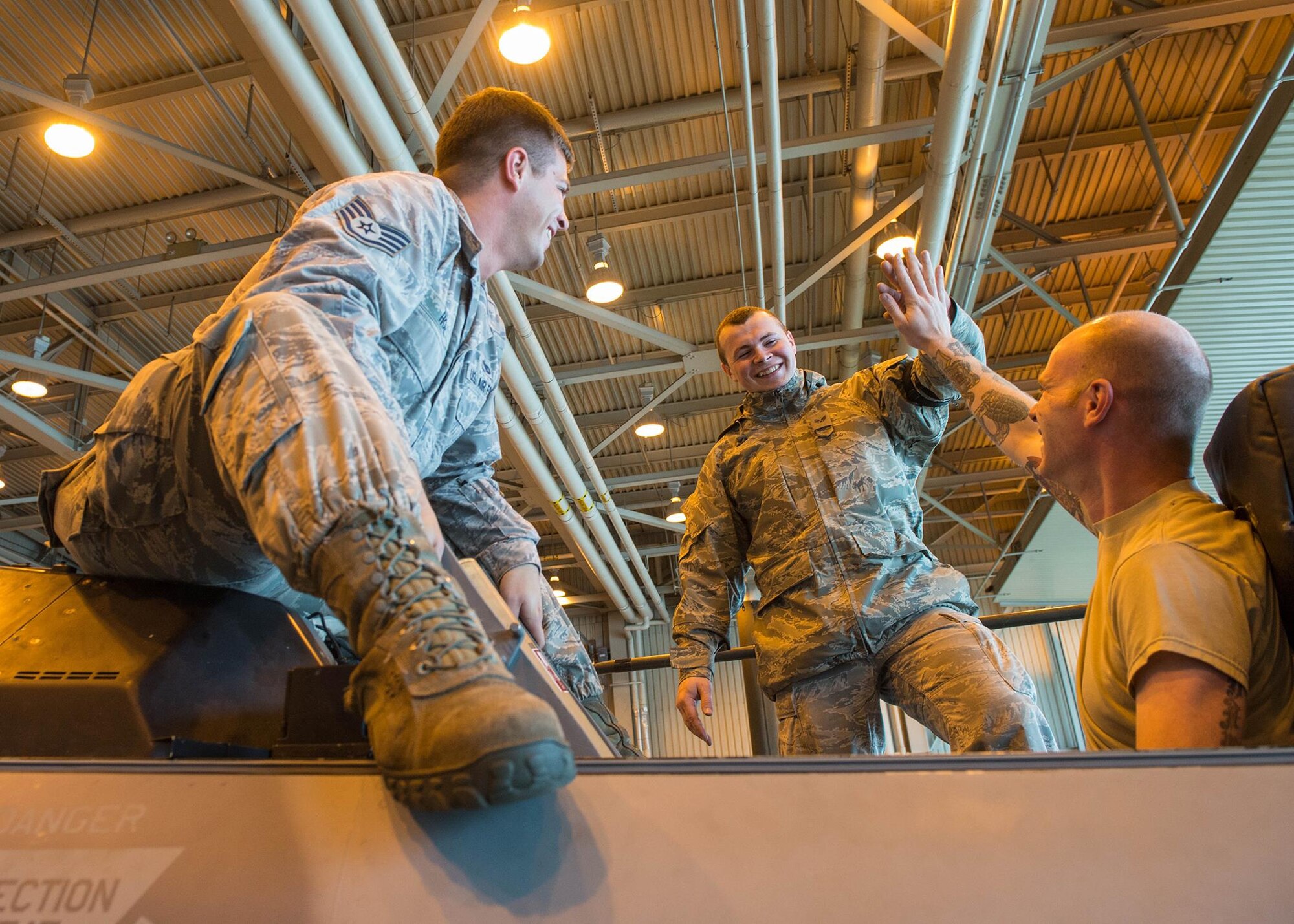 U.S. Air Force Staff Sgt. Corey Holt and Senior Airman Shane Sells, both assigned to the 8th Maintenance Squadron, Kunsan Air Base (AB), Republic of Korea, and Staff Sgt. Corey Holt, assigned to the 35th Maintenance Squadron, Misawa AB, Japan, all aircrew egress systems technicians, celebrate after bolting an injection seat that was difficult to reach into an F-16D Fighting Falcon aircraft Aug. 9, 2016, during RED FLAG-Alaska (RF-A) 16-3 at Eielson Air Force Base, Alaska. The maintenance Airmen combined skills, saving 50 percent on man-hours and temporary duty funds, increasing coverage from 12 to 24 hours during RF-A 16-3. (U.S. Air Force photo by Staff Sgt. Shawn Nickel)