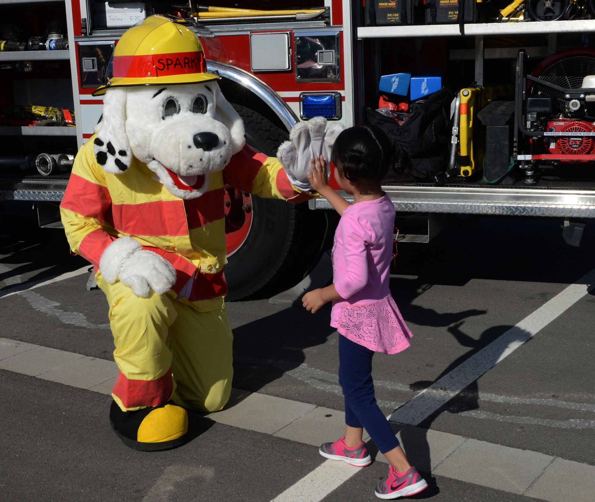 Sparky the Fire Dog gives a child a high-five at a block party Aug. 5, 2016, at Ramstein Air Base, Germany. All Department of Defense cardholders and their families with access to the base were able to attend the block party. (U.S. Air Force photo/ Airman 1st Class Joshua Magbanua)