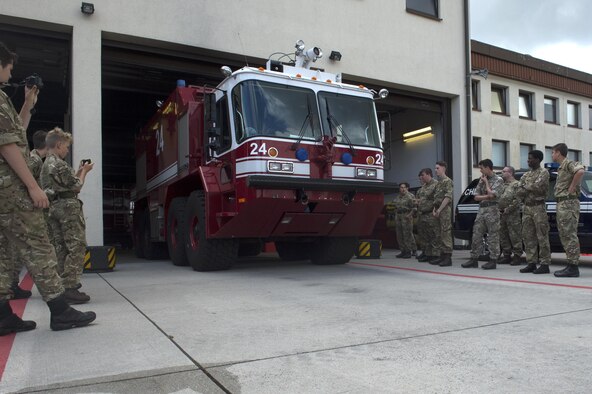 Members of Air Cadets, a United Kingdom-wide youth group sponsored by the Royal Air Force, watch as a 52nd Civil Engineer Squadron fire engine drives out of a garage during a tour at Spangdahlem Air Base, Germany, Aug. 9, 2016. Air Cadets received a guided tour of base assets from members of the 52nd Fighter Wing Community Relations, 52nd Maintenance Group and 52nd CES to include the F-16 Fighting Falcon fighter aircraft and fire department. (U.S. Air Force photo by Airman 1st Class Preston Cherry/Released)
