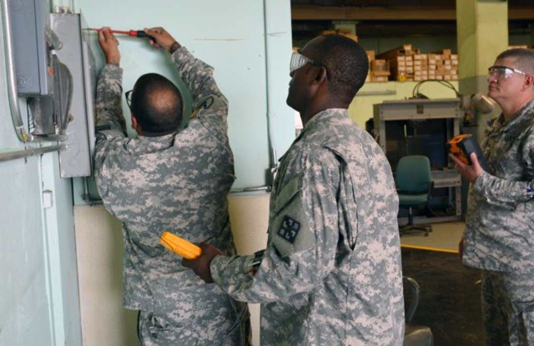 1st Lt. Anthony Richards, center, is supervising Sgt. 1st Class Julio Jimenez who is checking an electrical panel, while Maj. Arron Perry observes the work. Richards is a licensed electrician in the New York City area. (Photo Credit: John B. Snyder)