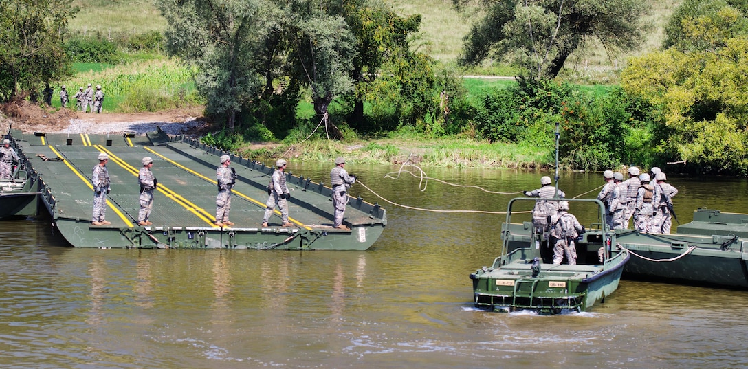 A soldier tosses a rope to a team member after securing it to a tree and a portion of an improved ribbon bridge on the Olt River near Voila, Romania, during Exercise Saber Guardian 16,  Aug. 1, 2016.  Army photo by 1st Sgt. Kevin Hartman