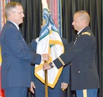 The symbolic passing of the Medical Education and Training Campus flag from Brig. Gen. James Dienst (left), director of the Defense Health Agency’s education and training directorate, to Col. Jack Davis (right) signals that the responsibility and authority of leading METC has been bestowed upon the new commandant.