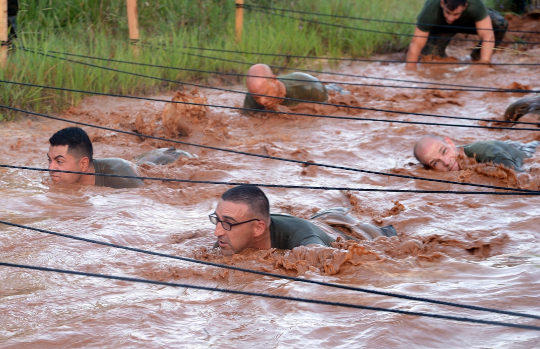 Marines with Headquarters Company East, Marine Corps Logistics Command, low-crawl through red Georgia clay mud pits during a motivation run held aboard Marine Corps Logistics Base Albany, July 28.