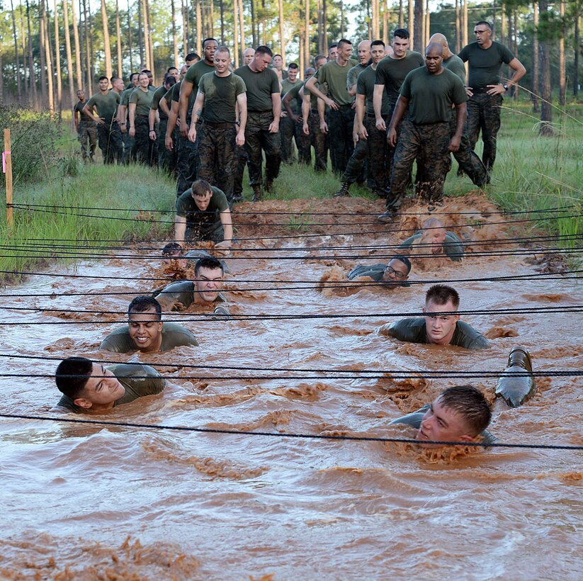 Marines with Headquarters Company East, Marine Corps Logistics Command, low-crawl through red Georgia clay mud pits during a motivation run held aboard Marine Corps Logistics Base Albany, July 28.